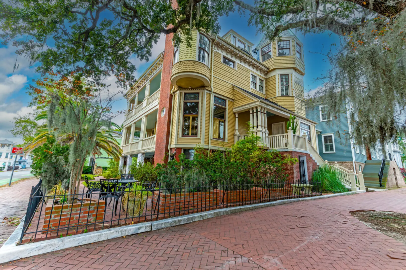 A large yellow house with a red brick driveway.